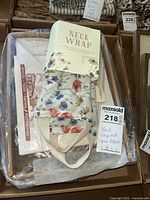 Tray containing the potpourri box and folded neck wrap showing floral print and packaging label