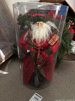 Old World Santa doll in clear cylindrical plastic case, showing full front view with detailed clothing and accessories.