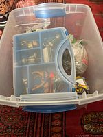 Clear bin with blue compartment case holding multiple Playmobil figures and accessories