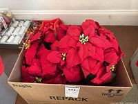 Box filled with multiple red faux poinsettia stems
