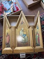 Full frontal photo of the religious triptych showing the Mother and Child central panel and the left and right saint panels with pointed gothic-style frame tops.