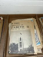 Stack of headline newspapers with top visible titled 'The Times Coronation of Elizabeth II'