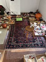 Full view of the rug on a wooden floor with boxes of miscellaneous items around it, showing the overall design and size.