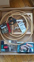 Top view of the lot showing wooden embroidery hoops, large and small scissors, strip cutter, and plastic cases with thread and sewing accessories.
