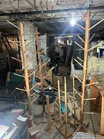Wide view of the complete set of wooden tree stands in a basement setting with other stored items around.