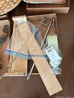 Photo showing metal towel bars, wooden shelf, and decorative cast iron piece with mounting hardware in a box.