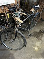 Black vintage Philips bicycle with steel frame and front basket support shown side view in basement setting.