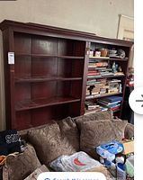 Front view of the bookcase showing shelves with some empty and some containing books and items, as well as the dark wood finish and scratches.
