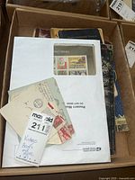 Photo showing a box containing vintage books and circus posters with an envelope and handwritten label.