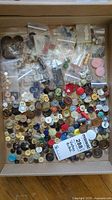 Photo showing a large assortment of vintage buttons in different colors, sizes and materials inside a box with small bags.