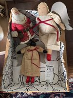 Photo showing all three dolls together in a shallow box. Includes plush Santa Claus doll in red suit and two fabric angels, one light-skinned and one black-skinned.