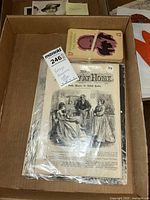 Vintage ephemera box containing Sunday at Home magazine on top with an illustrated cover showing a Victorian family scene, alongside a set of 17 'Horrors of the Screen' monster movie cards tied with a rubber band.
