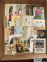 A box containing assorted vintage greeting cards, with various artistic and holiday-themed designs, showing the variety and quantity of cards included in the lot.