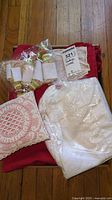 Overview photo showing the vintage lace crochet pillow, wrapped tassels, white lace table linen, and red fabric linens.