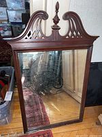Full view of the vintage rectangular mirror with wood frame and ornate top with finial.