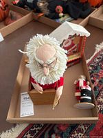 Handcrafted Jax Santa with fluffy white beard and glasses sitting inside a wooden box with a framed Santa image and a small Santa Mouse figurine nearby.