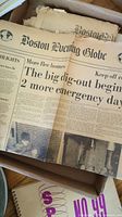 Photo showing vintage Boston Globe newspaper with headline about a hurricane emergency in 1938, page visibly creased and aged.