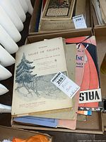 Box with vintage sheet music and lesson books showing a stack with one clear vintage sheet music titled "Night of Nights"
