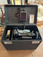 Singer sewing machine and accessories inside open black carrying case