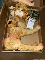 Top view of three vintage stuffed animals in a cardboard box including a large camel and two smaller animals