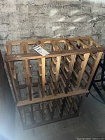 Wooden wine rack against textured grey wall, showing top and side view.