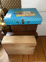 Wooden automatic rewinding spin top box with metal clasp, wooden tray, wooden cabinet with dovetailed joints, and blue bingo game box stacked together.