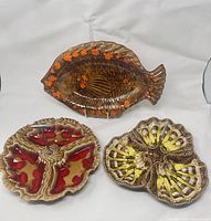 View of all three mid century pottery serving dishes including fish-shaped, tri-section red glaze, and four-section yellow glaze dishes