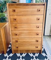 Front view of tall narrow mid-century dresser, showing six teak veneer drawers with recessed integrated wooden pull handles.
