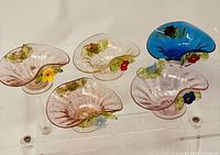 Set of five Victorian Venetian art glass salt cellars arranged on clear display stand, showing variety of flower colors and translucent glass body with aventurine accents.