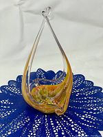 Full view of vintage glass basket on blue doily, showing colors and shape