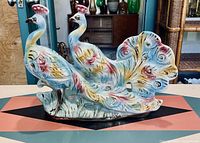 Full view of large ceramic peacock pair sculpture with multicolored glaze and gold gilt.