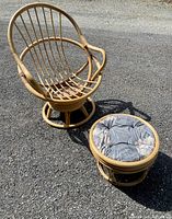 Rattan swivel chair with no cushion and matching ottoman with cushion on asphalt surface in daylight