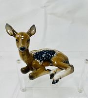 Front-left angle view of the ceramic deer figurine showing its facial details and seated pose.
