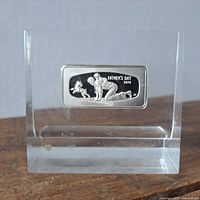 Front view of clear rectangular paperweight with embedded silver plaque depicting man playing with dog and Father's Day 1976 inscription.