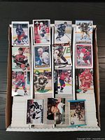 Top view of multiple stacks of hockey cards arranged vertically in a storage box, showing front cards of different players and teams from various years and brands.