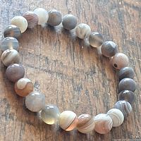 Top view of the round agate beads on the stretch bracelet resting on wood surface, showing variety of colors and banding.