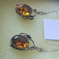 Close-up image showing one pair of amber earrings with sterling silver settings and hooks, highlighting the amber stones and silver craftsmanship.