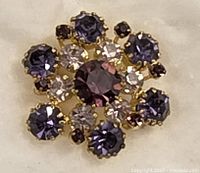 Front view of the brooch showing purple and white Austrian crystals in a gold-tone setting.