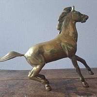 Side front angle of brass horse sculpture showing the raised front legs and detailed mane