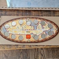 Oval display holder showing 13 Canadian quarters from 1999 arranged around the edge with a red icon and Canada Millennium 1999 text and map background.