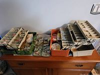 Two open fishing tackle boxes showing multiple trays with flies, lures, weights, lines, and other fishing accessories organized in compartments.
