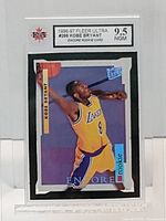 Front of the 1996-97 Fleer Ultra Kobe Bryant Rookie Card graded 9.5 NGM by KSA, showing the player mid-dunk in Lakers uniform with orange basketball and branding details.