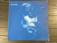 Front cover of the album showing blue monochromatic close-up photo of Joni Mitchell's face with visible wear.