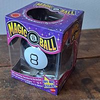 Front view of Magic 8 Ball in original packaging with purple star-themed box and visible '8' on the toy.