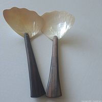 Two salad servers with mother of pearl blades and dark and lighter teak handles, showing full length.