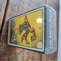 Side view of the sealed tarot deck box showing the Fool card artwork and packaging in shrink wrap with clear print of "The Smith-Waite Centennial Tarot Deck".