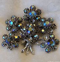 Front view showing silver-tone metal floral brooch with multiple colorful small rhinestones arranged as a flower bouquet, about 2 inches across.