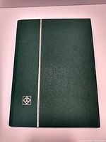 Closed green binder used to house the stamp collection