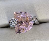 Close-up view of the large half-moon shaped pink stone flanked by two small round white stones on the sterling silver ring.