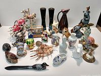 Wide view of all items grouped together on a white surface showing various small decorative and figurine items including birds, flowers, and small animal shapes.